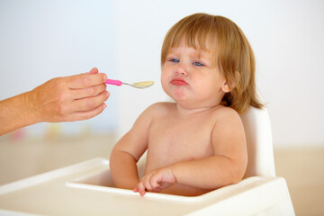 Baby, chair and eating food or unhappy mood for health meal, childhood development or upset. Hand,...