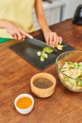 Fototapeta na wymiar cropped woman cutting fresh fruits while preparing vegetarian salad near honey and sesame seeds