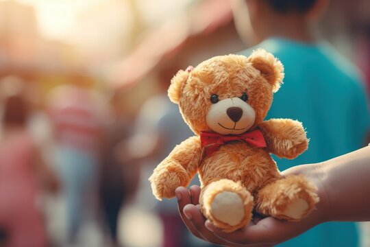 Poignant image of a child's hand receiving a teddy bear at a charity event, shallow depth of field with AI