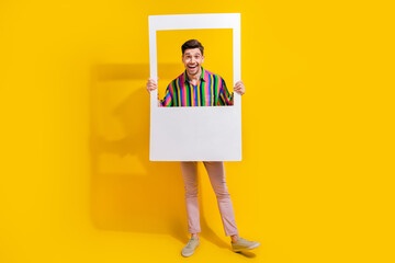 Photo of funny face grimace guy joking in stylish old school outfit holding paper portraits frame...
