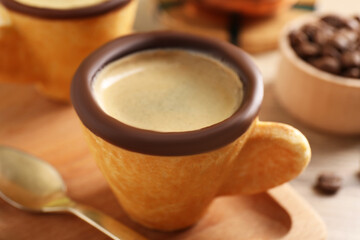 Delicious edible biscuit cup with espresso and board on table, closeup