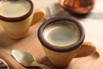 Delicious biscuit cups with coffee and board on table, closeup