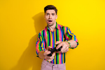 Photo of young man in striped trendy vintage shirt playing games wireless joystick when see he lose...