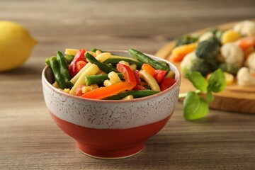 Frozen vegetables in bowl on wooden table, closeup