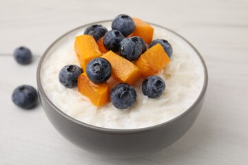 Bowl of delicious rice porridge with blueberries and pumpkin on white table, closeup