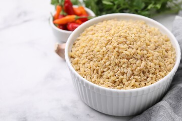 Raw bulgur in bowl on table, closeup