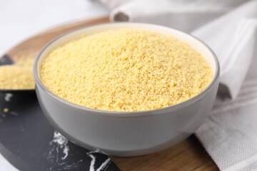 Raw couscous in bowl on table, closeup