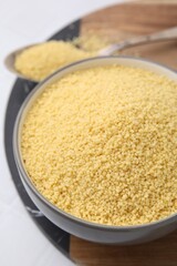 Raw couscous in bowl on table, closeup