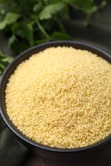 Raw couscous in bowl on table, closeup