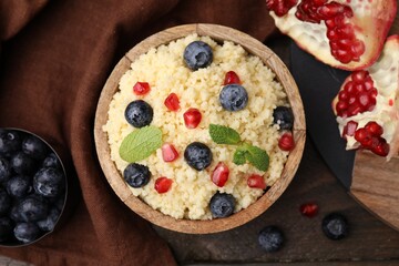 Bowl of tasty couscous with blueberries, pomegranate and mint on table, flat lay
