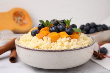 Bowl of tasty couscous with blueberries, pumpkin and mint on table, closeup
