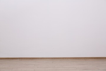 Empty white wall and wooden floor indoors, space for text