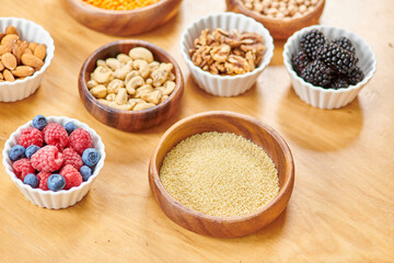 bowl with couscous near various nuts and fresh berries on table, plant-based nutrition concept
