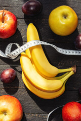 bunch of bananas, red peppers, apples and plums in the sun vegetable basket	