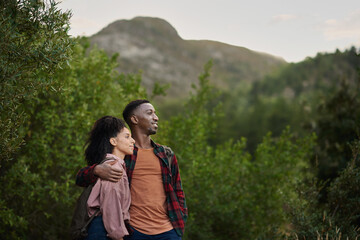 Young multiethnic couple smiling at the scenic view while out hiking