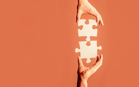 Closeup hands of man connecting jigsaw puzzle. Two hands trying to connect couple puzzle. Hand connecting jigsaw puzzle. Man hands connecting couple puzzle piece