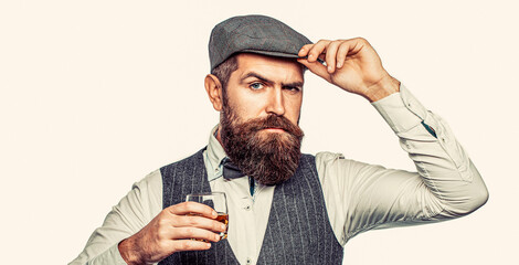 Bearded in is holding a glass of whiskey. Sommelier tastes expensive drink. Drinking whiskey,...
