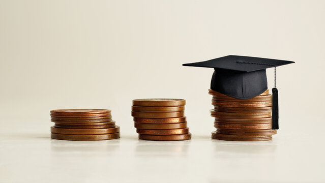 Black graduation cap on stocks of coins, depicting strong effort for students who study hard for a future career. Graduate study abroad program for higher degree knowledge. College grants