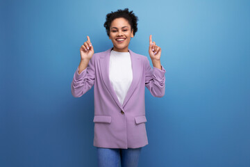 young positive successful latin business woman with tousled hairdo dressed in a jacket points her finger at having an idea