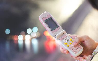 Teenager hand using pink flip phone for Y2K nostalgia trend fashion