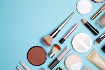 Face powder and other decorative cosmetic products on light blue background, flat lay. Space for...