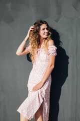 Beautiful woman in a dress against the wall on the street for a walk