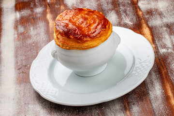Cream-soup of wild mushrooms baked under puff pastry. On a wooden background.