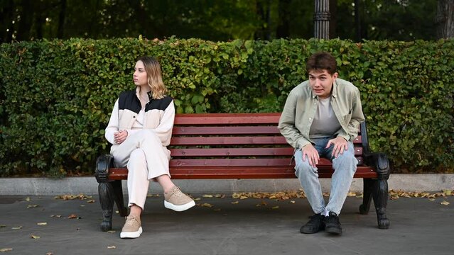 A timid, interested guy sits down and wants to meet a young woman sitting on a bench in the park. Comical depiction of dating or pickup