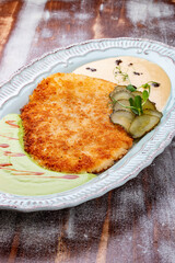 Viennese chicken schnitzel with sauces and pickles. Haute cuisine. On a wooden background.