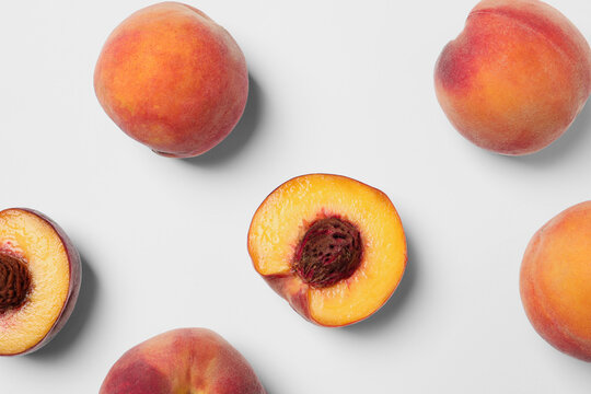 Cut and whole fresh ripe peaches on white background, flat lay