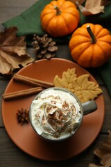Flat lay composition of tasty pumpkin spice latte with whipped cream in cup on wooden table