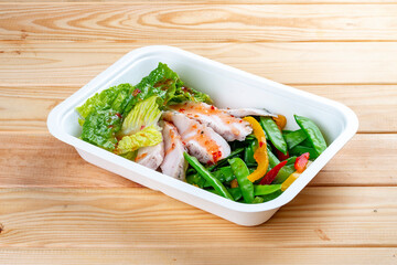 Turkey filet with fresh vegetables. Healthy diet. Takeaway food. Eco packaging. On a wooden background.