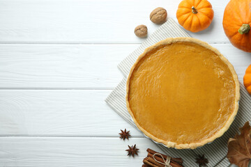 Fototapeta premium Delicious pumpkin pie and ingredients on white wooden table, flat lay. Space for text