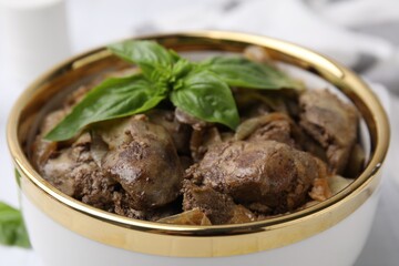 Delicious fried chicken liver with onion and basil in bowl on table, closeup