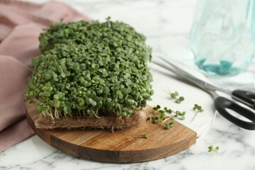 Fresh daikon radish microgreen and scissors on white marble table, closeup. Space for text