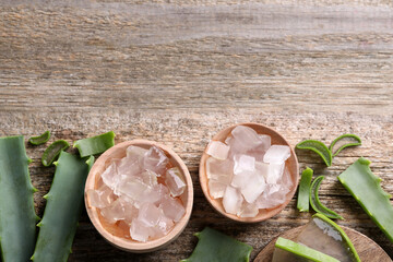 Aloe vera gel and slices of plant on wooden table, flat lay. Space for text