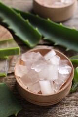 Aloe vera gel and slices of plant on wooden table, closeup