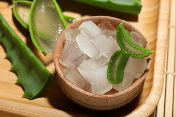 Aloe vera gel and slices of plant on bamboo mat, closeup