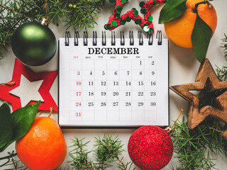 Merry Christmas. Happy New Year. Calendar and Christmas decorations lying on an empty table. Close-up, view from above. Congratulations for loved ones, relatives, friends, colleagues