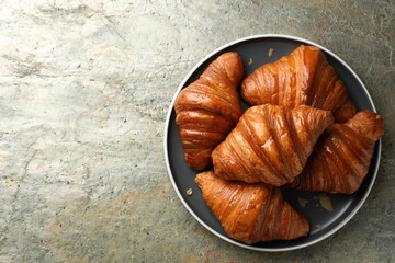 Delicious fresh croissants on grey textured table, top view. Space for text