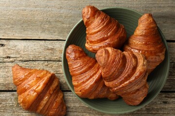 Delicious fresh croissants on wooden table, flat lay