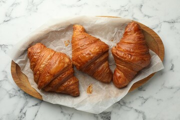 Tray with tasty croissants on white marble table, top view