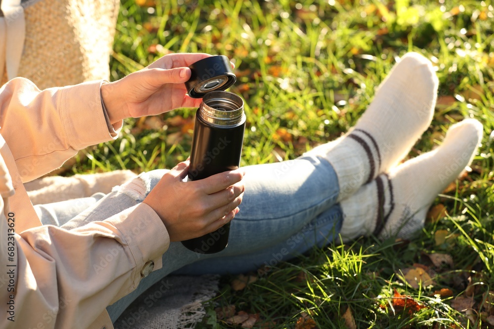 Canvas Prints Woman opening thermos on green grass outdoors, closeup