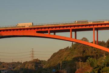 夕暮れに配送を急いで橋梁を渡るトラック