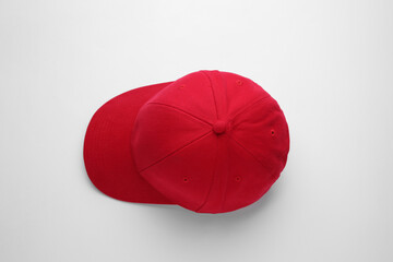 Stylish red baseball cap on white background, top view