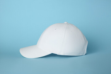 Stylish white baseball cap on light blue background