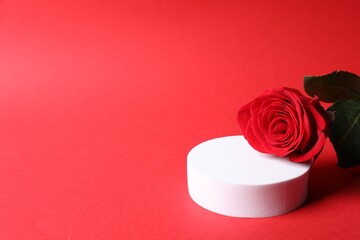 Stylish presentation for product. Round podium and beautiful rose on red background, space for text