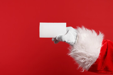 Merry Christmas. Santa Claus holding blank card on red background, closeup. Space for text