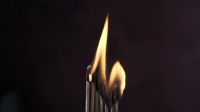 a row of matches are lit on a dark background
