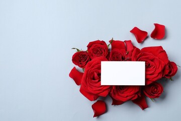 Blank card, beautiful red roses and petals on grey background, top view. Space for text